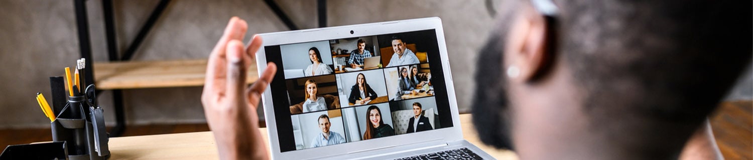 man speaking to a group of people in a virtual meeting on laptop